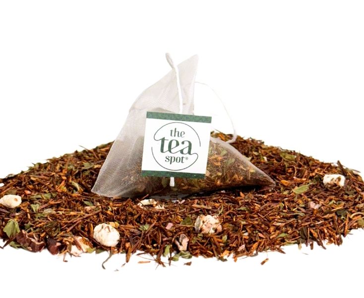 
                  
                    a tea bag sits atop a pile of loose leaf tea, the tea is a rooibos herbal blend with marshmallows
                  
                