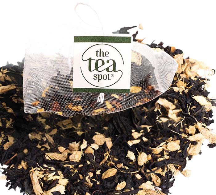 a sachet of black tea ginger peach sits on top of a pile of ginger peach loose leaf tea