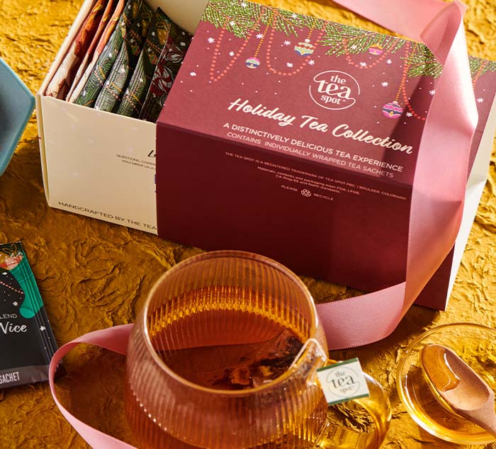 
                  
                    a box reading holiday tea collection sits behind a cup of tea with a tea bag in it
                  
                