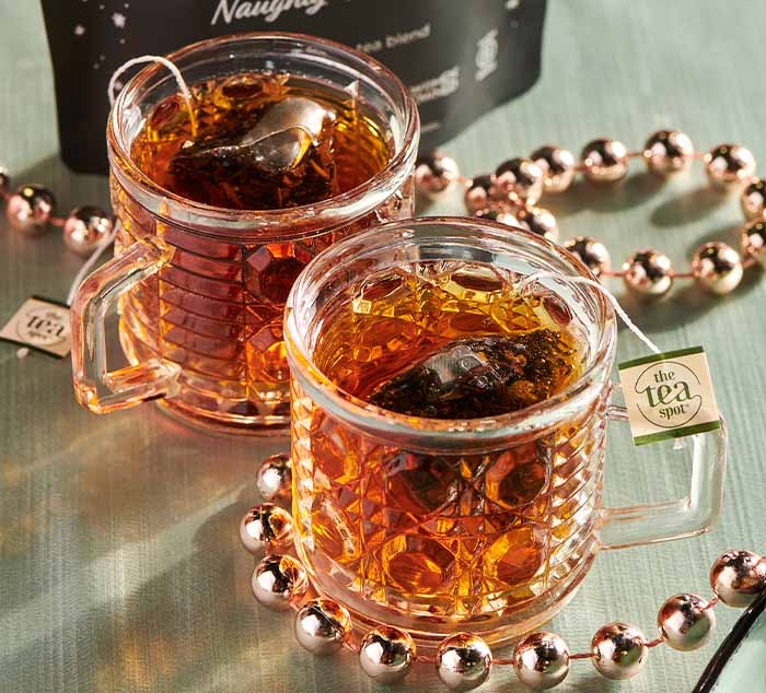 
                  
                    two glasses of black tea sit on a table with tea bags brewing in them surrounded by decorations
                  
                