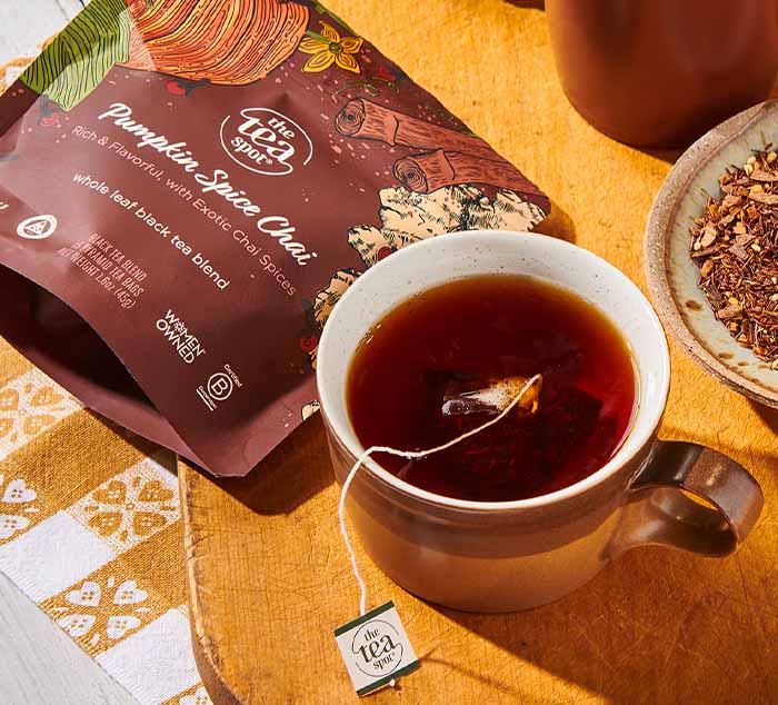 
                  
                    a bag reading pumpkin spice chai sits next to a cup of brewed tea with a tea bag in it
                  
                