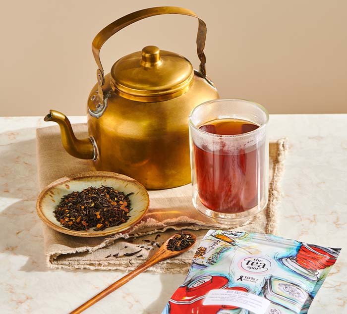 
                  
                    rise and chai tea brewed in a cup sitting next to loose leaf chai tea, a bag of rise and chai, and a gold tea pot
                  
                