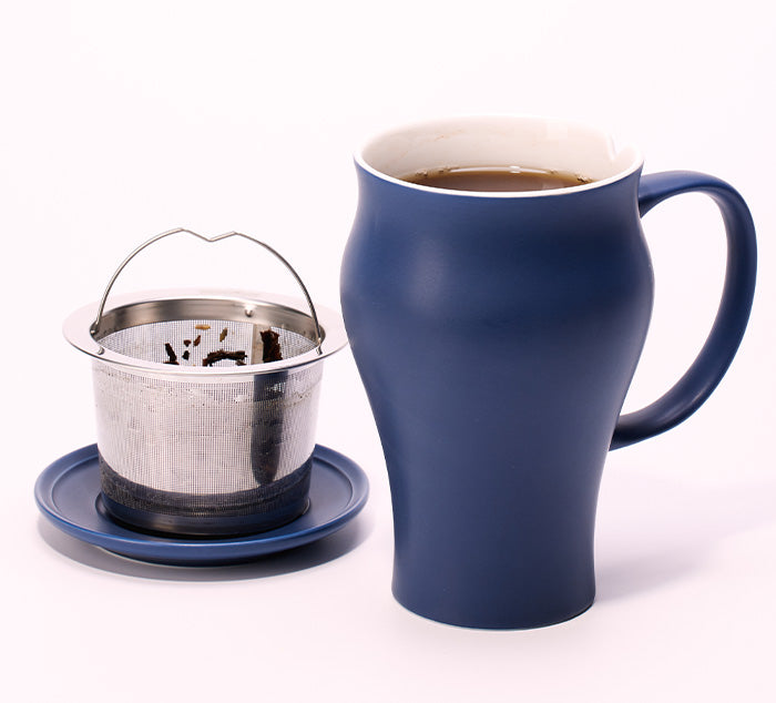 
                  
                    a brewed up of tea sits next to a stainless steel infuser sitting in a saucer
                  
                