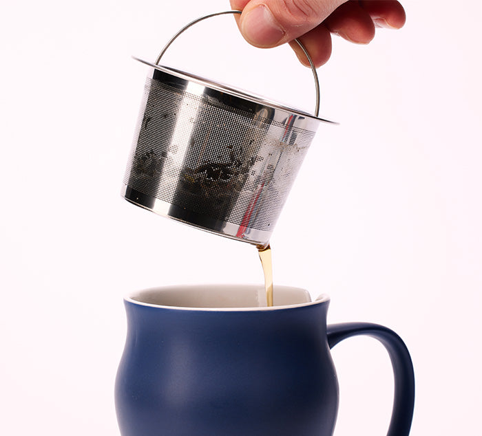 
                  
                    a hand removes a large stainless steel infuser from a ceramic tea mug
                  
                