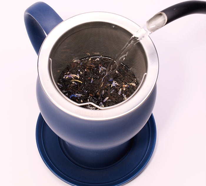 
                  
                    boiling water is poured on top of loose leaf tea leaves in a ceramic tea cup
                  
                