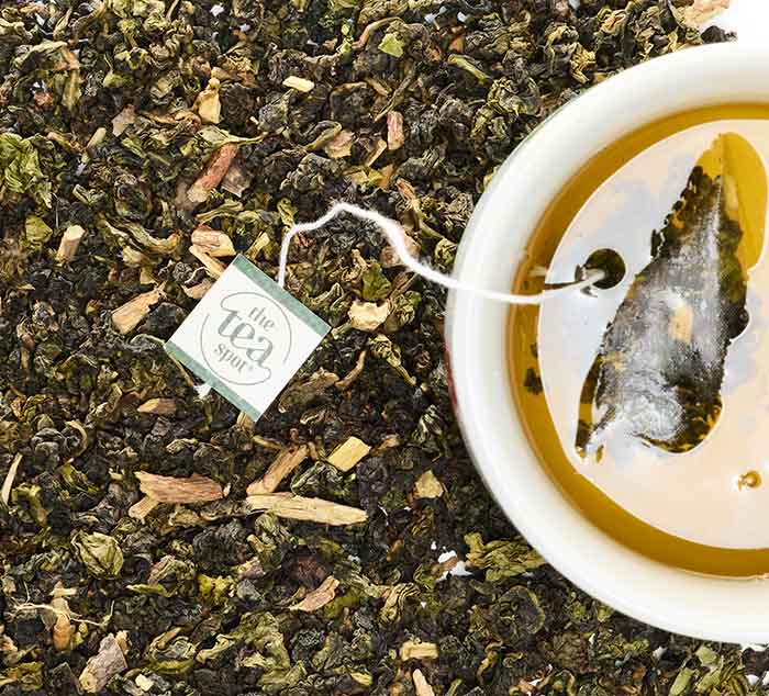 
                  
                    Close-up of Sugar Cookie Oolong tea leaves with a tea bag steeping in a teacup
                  
                